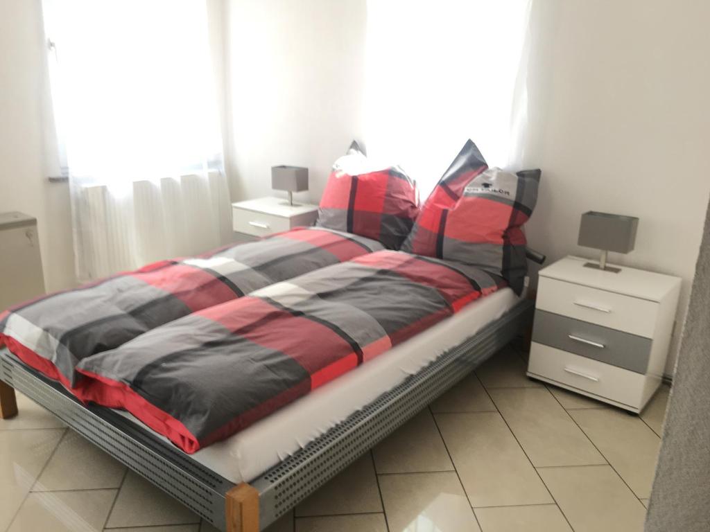 a bed with a red and black comforter in a bedroom at Ferienwohnungen Honberg in Tuttlingen