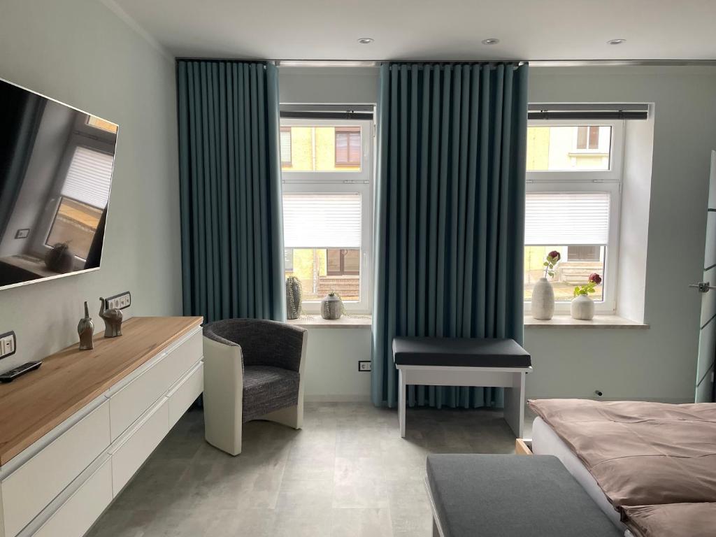 a bedroom with a bed and a chair and a window at Ferienwohnung Silberzeit in Annaberg-Buchholz