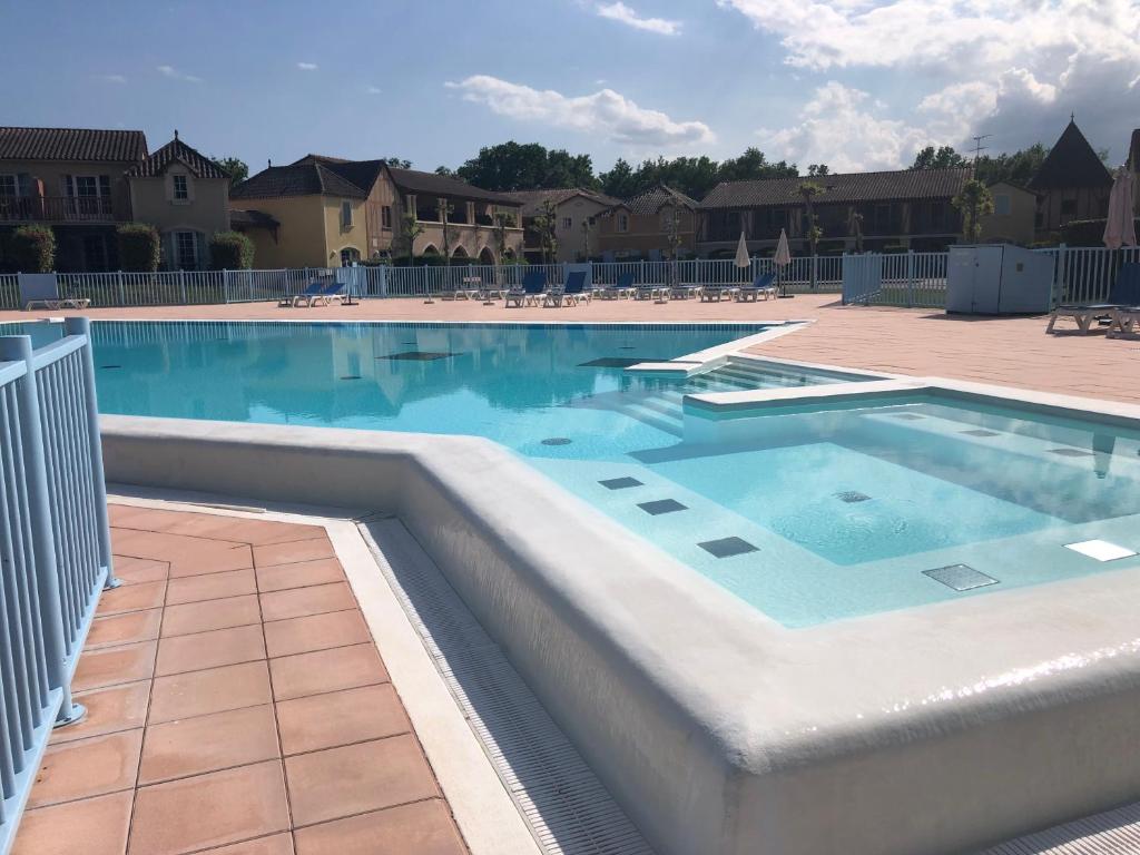 uma grande piscina com água azul em Petite maison dans Résidence em Monflanquin