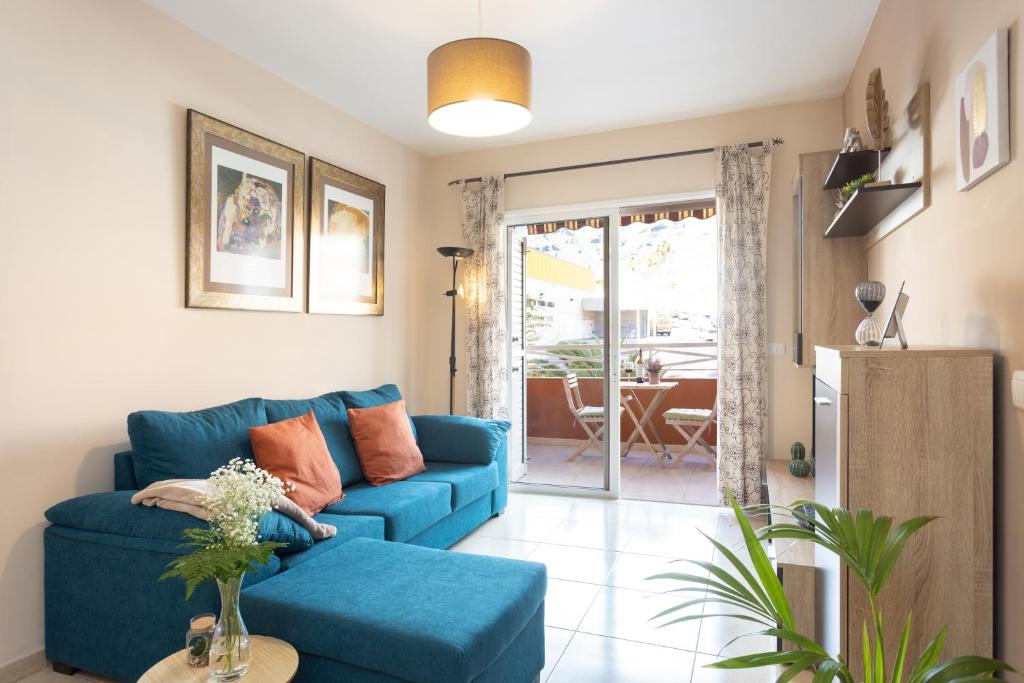 sala de estar con sofá azul y mesa en Vivienda vacacional en Caletillas Piscina yWIFI, en Candelaria
