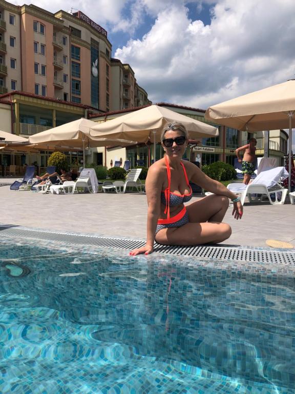 una mujer en bikini sentada junto a una piscina en Karos Gold 813 Wellness Apartman, en Zalakaros