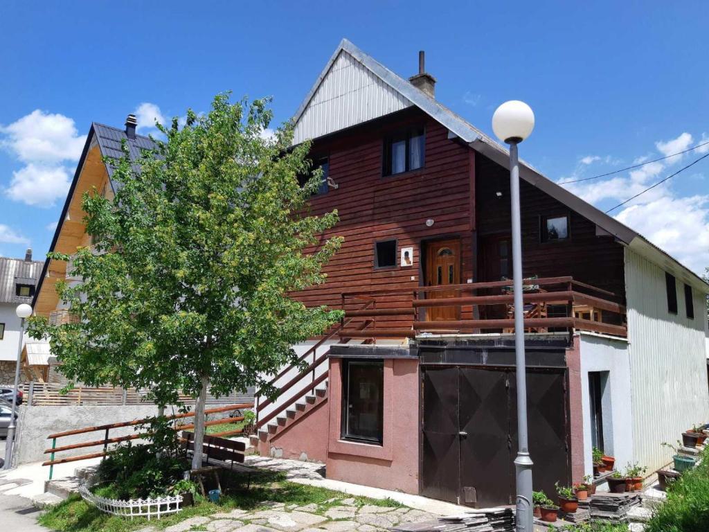 a large wooden house with a tree in front of it at Apartments Sipcic in Žabljak