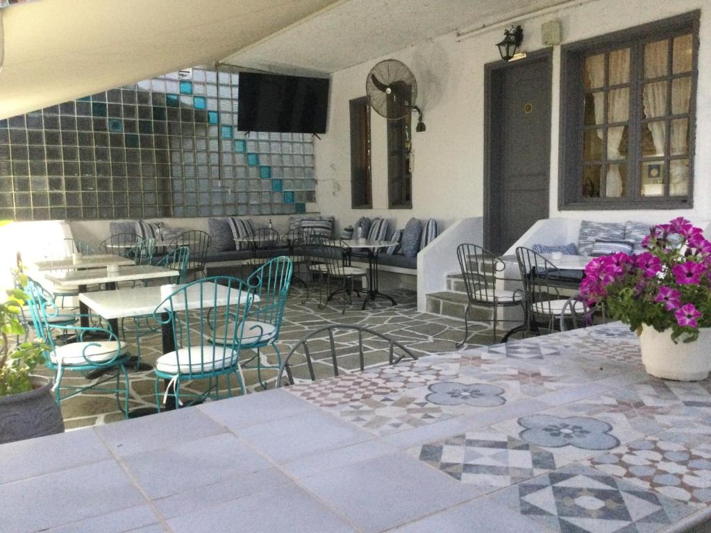 un patio con mesas, sillas, mesas y flores púrpuras en Hotel Sweet Home, en Neos Marmaras