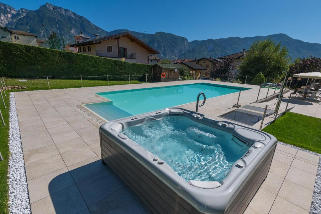a hot tub on a patio next to a swimming pool at Hotel Lucia in Levico Terme