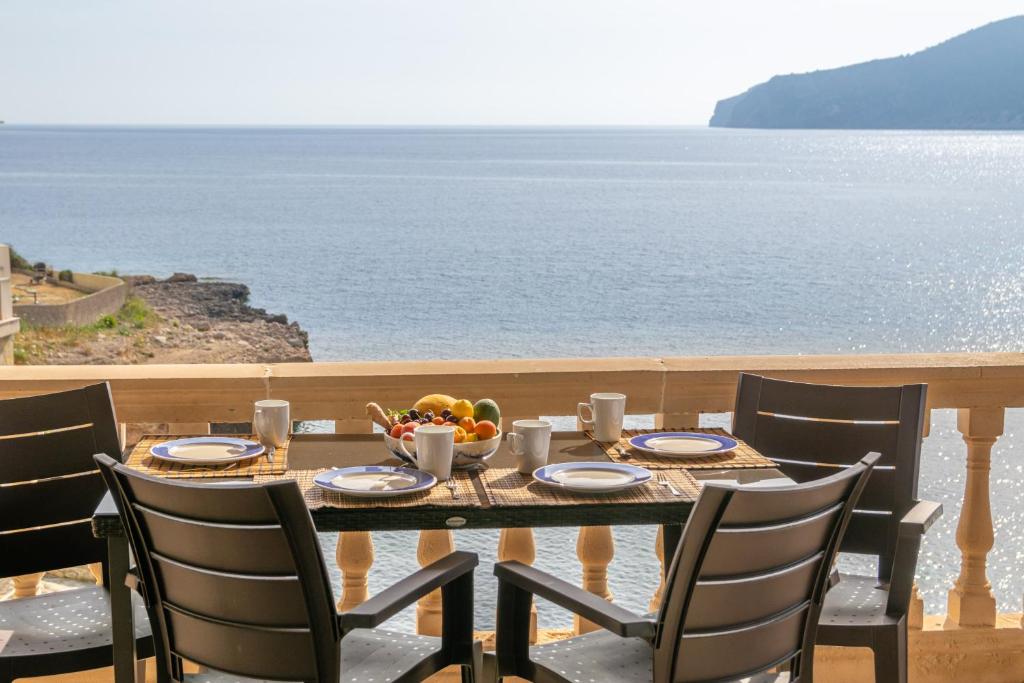 a table with a bowl of fruit and a view of the ocean at Vista Azul 1 in Sant Elm