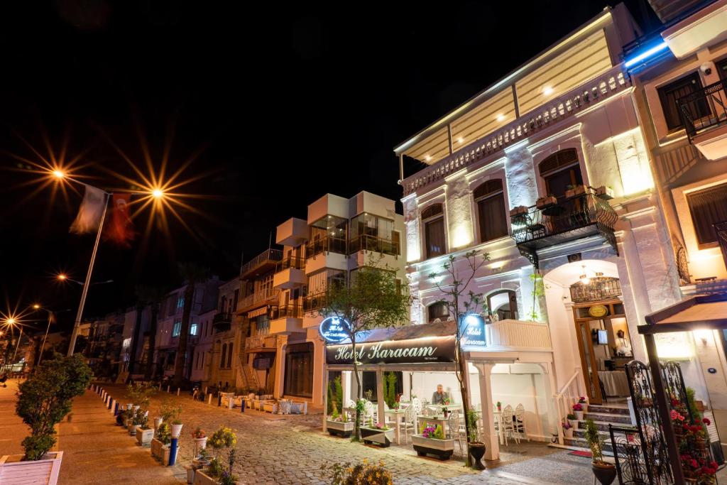 una strada di città di notte con edifici e luci di Hotel Karacam a Foça
