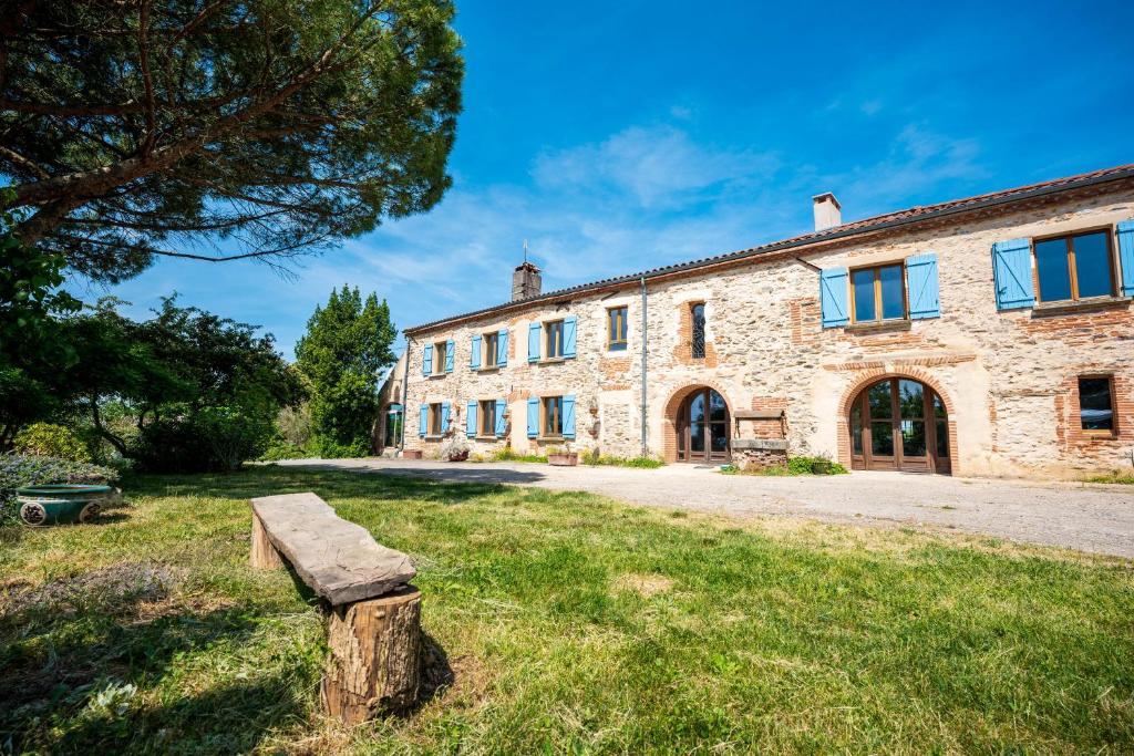 a stone house with a bench in front of it at Chambres et table d'hôtes - Les Jardins de la Longagne in Saussenac