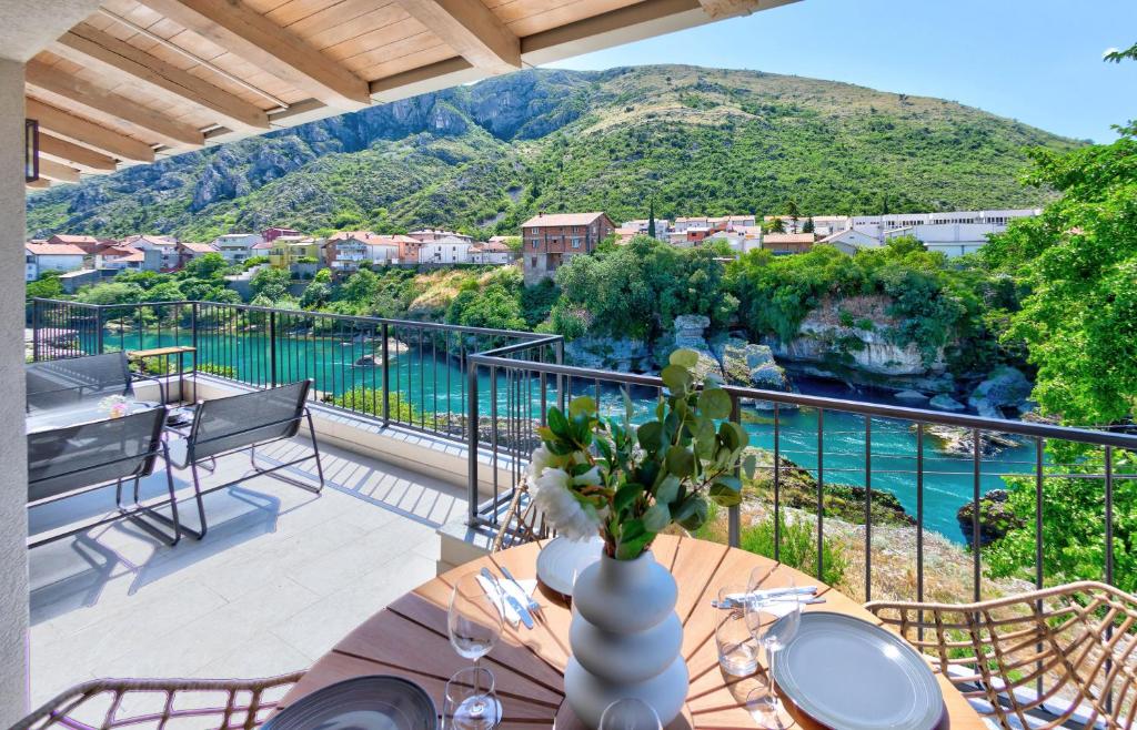 einen Balkon mit einem Tisch und Blick auf das Wasser in der Unterkunft Villa Amaleo in Mostar