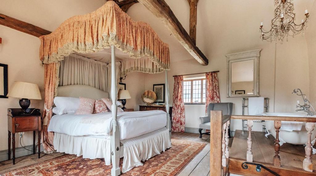 a bedroom with a canopy bed and a tub at Lavish Tudor Estate & Gardens - Sleeps 25 in Hales