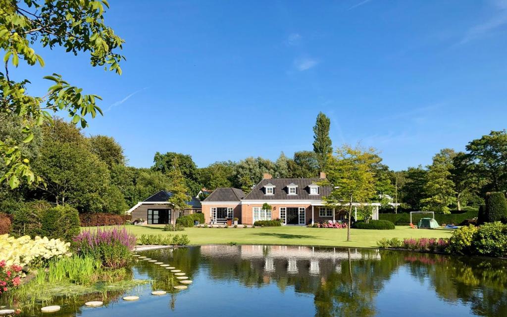 a large house with a pond in front of it at Buitenliefde, romantisch verblijf voor 2 personen in Heiloo