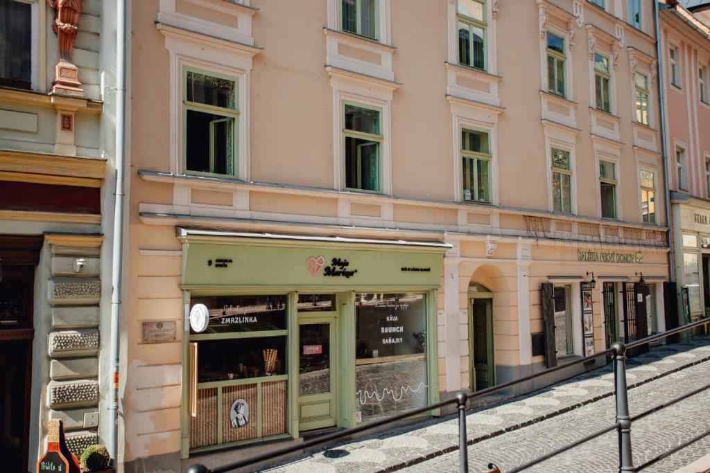 un bâtiment rose avec un magasin dans une rue dans l'établissement Priestranný apartmán Moja Marína® v srdci Štiavnice, à Banská Štiavnica