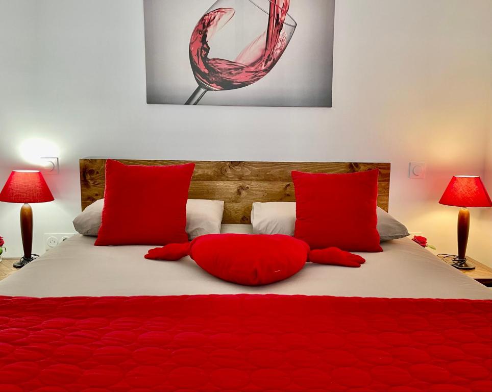 a bed with red pillows and a red blanket at Maison d'hôtes Romarine in Le Bouscat