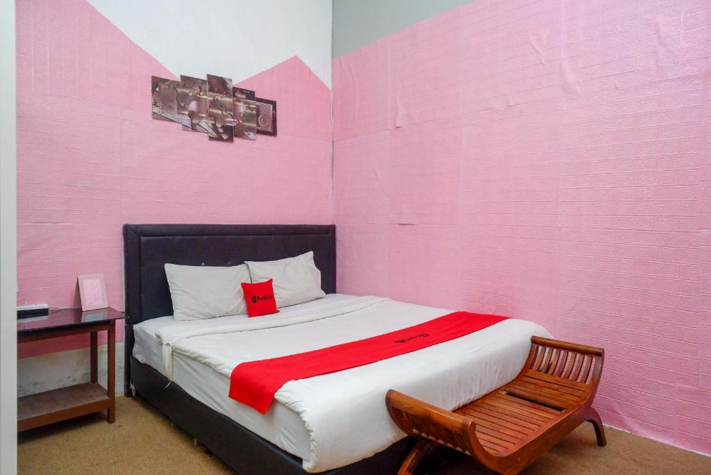 RedDoorz At Golden Inn Tugu Yogyakarta في يوغياكارتا: غرفة وردية مع سرير وكرسي