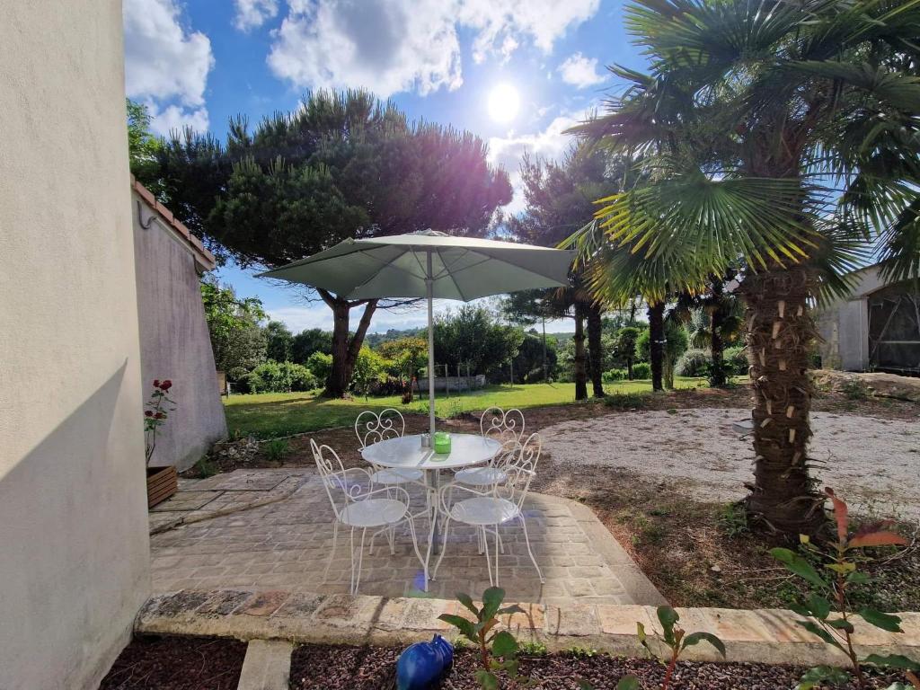 una mesa y sillas bajo una sombrilla en un patio en L'hacienda de Soubran, Le Gîte à Grand-mère, classé 4 étoiles, en Soubran