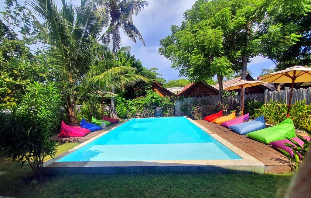 a swimming pool with colorful chairs next to a house at United Colors of Gili in Gili Meno