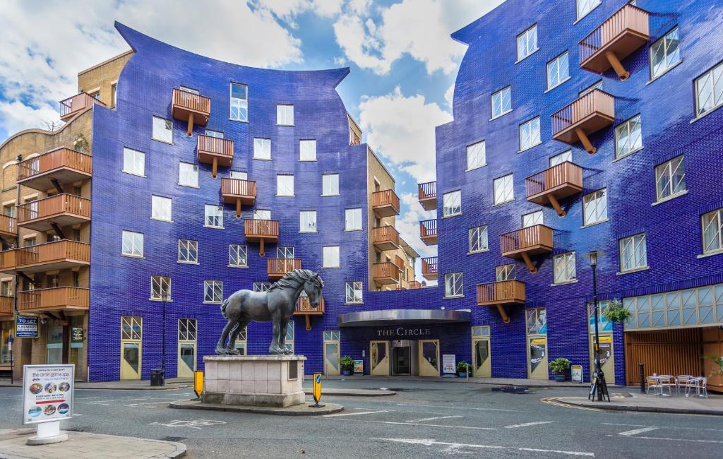 un edificio azul con una estatua de caballo delante de él en London Tower Bridge Apartments en Londres