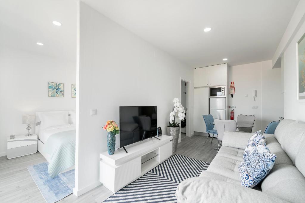 a white living room with a couch and a tv at Santa Luzia I by An Island Apart in Funchal
