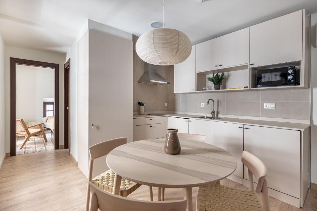 a kitchen with white cabinets and a table and chairs at Apartamentos Líbere Málaga la Merced in Málaga
