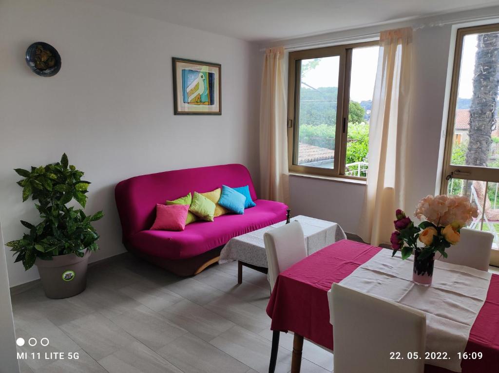 een woonkamer met een roze bank en een tafel bij Apartment and Room Bitinada in Rovinj