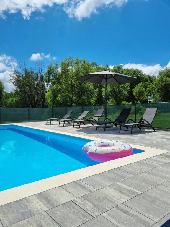 a swimming pool with chairs and an umbrella and an inflatable at Boutique Apartments Nikola Tesla in Rakovica