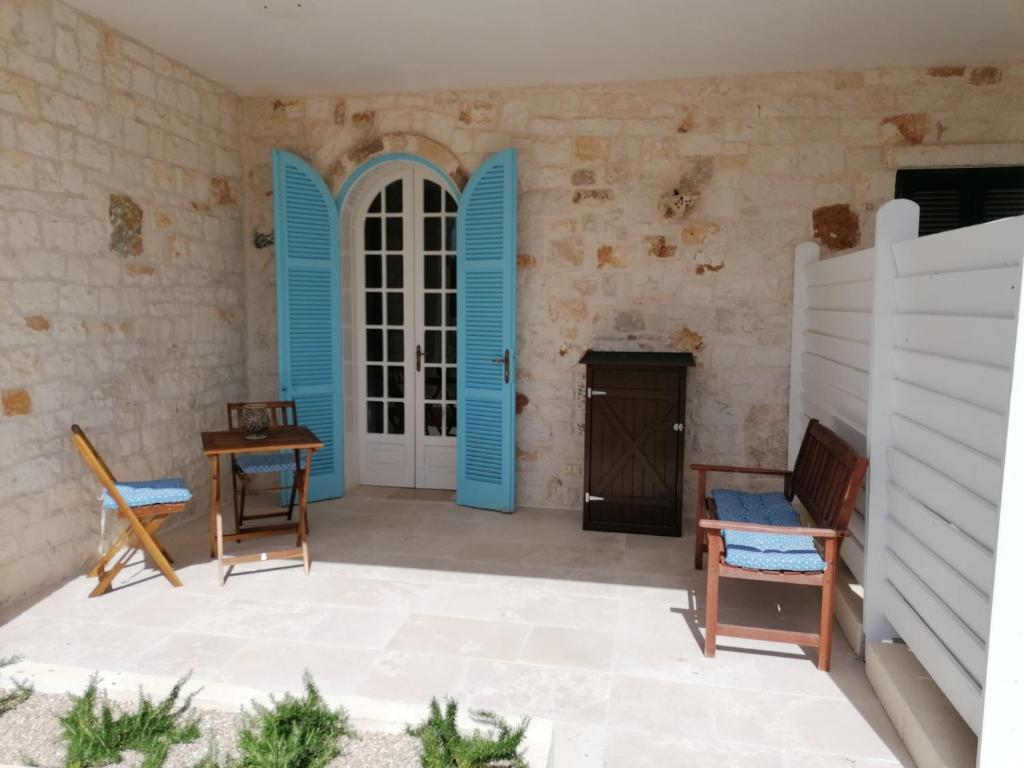 a patio with blue doors and a table and chairs at Ramasole in Ostuni