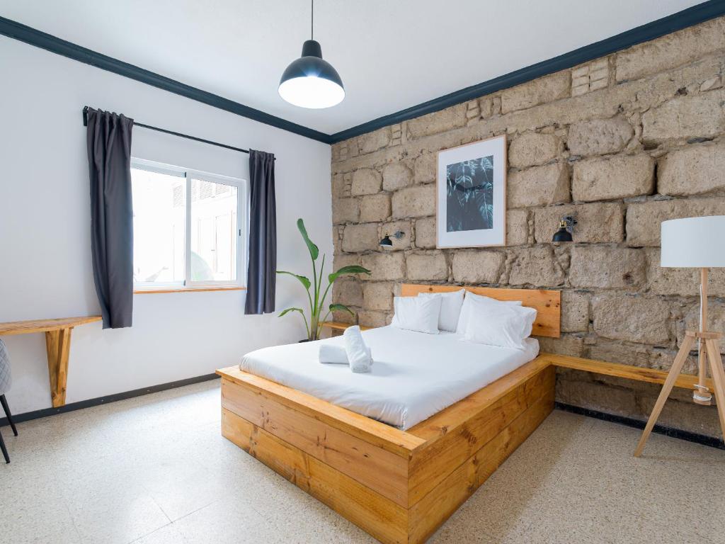 1 dormitorio con cama de madera y pared de ladrillo en Cathedral Apartment, en Las Palmas de Gran Canaria