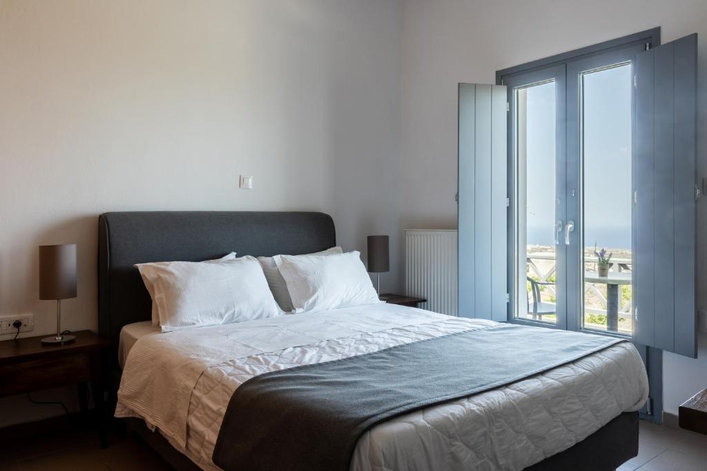 sypialnia z dużym łóżkiem i dużym oknem w obiekcie Ampelos Executive Houses w mieście Pirgos
