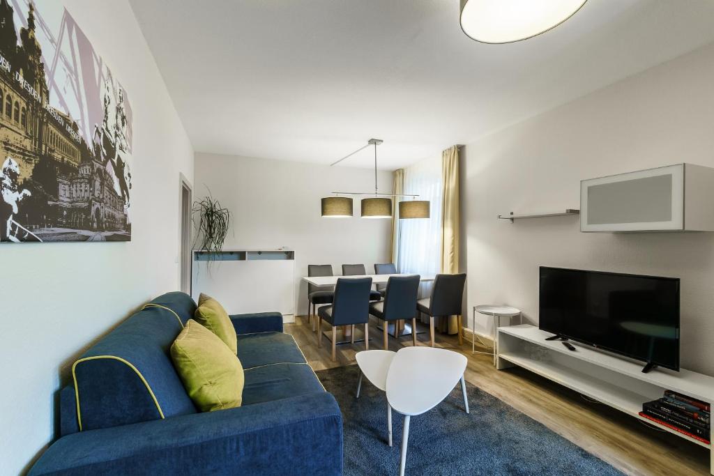 a living room with a blue couch and a tv at Familienapartment nahe der Frauenkirche in Dresden