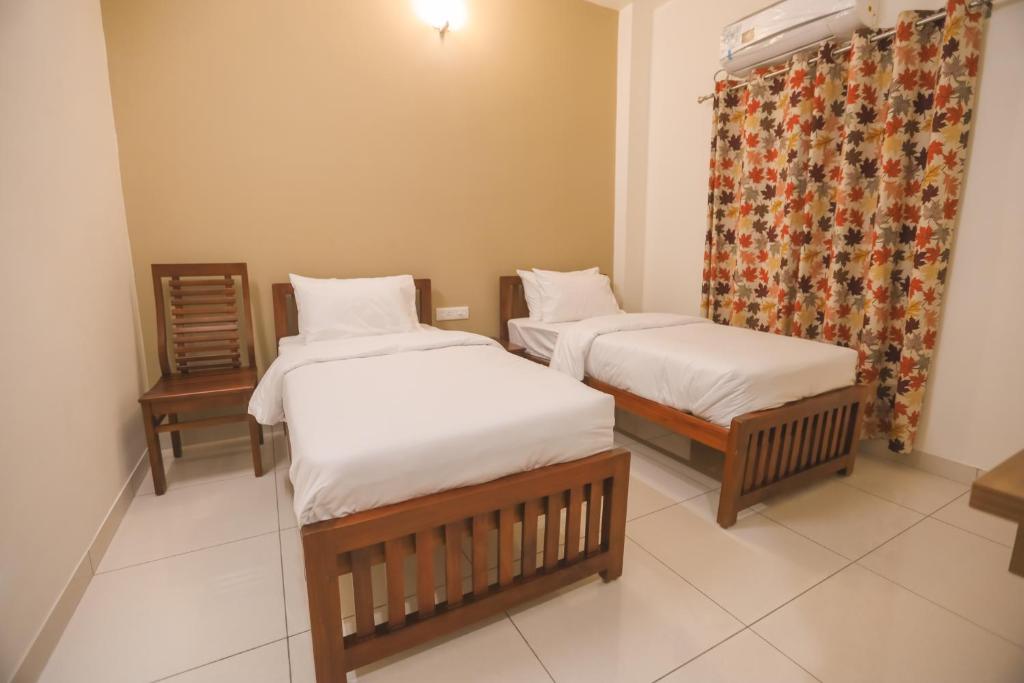 2 łóżka pojedyncze w pokoju z zasłoną w obiekcie VIPRA HOTEL w mieście Coimbatore