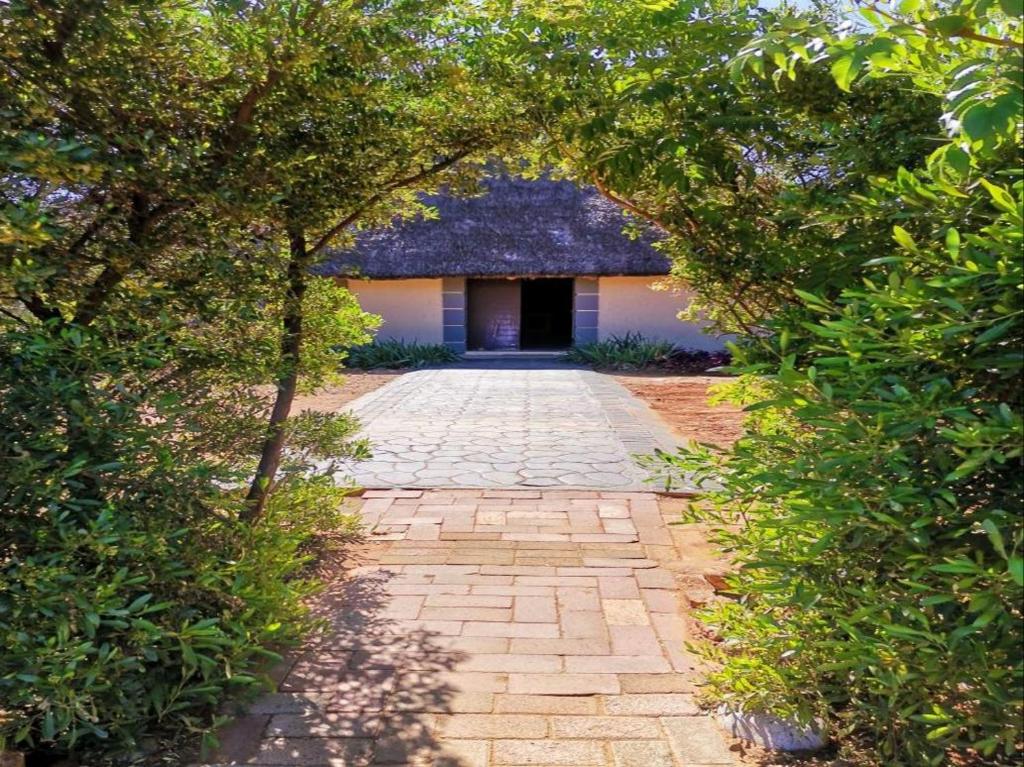 un camino de piedra que conduce a un edificio con puerta en Monakaladi Gardens Function Venue and Homestead, en Mahikeng