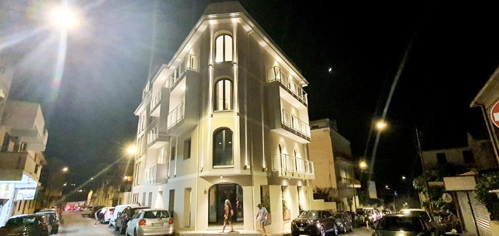 Solmaris Tropea Rooms & Suites في تروبيا: مبنى ابيض كبير على شارع المدينة بالليل