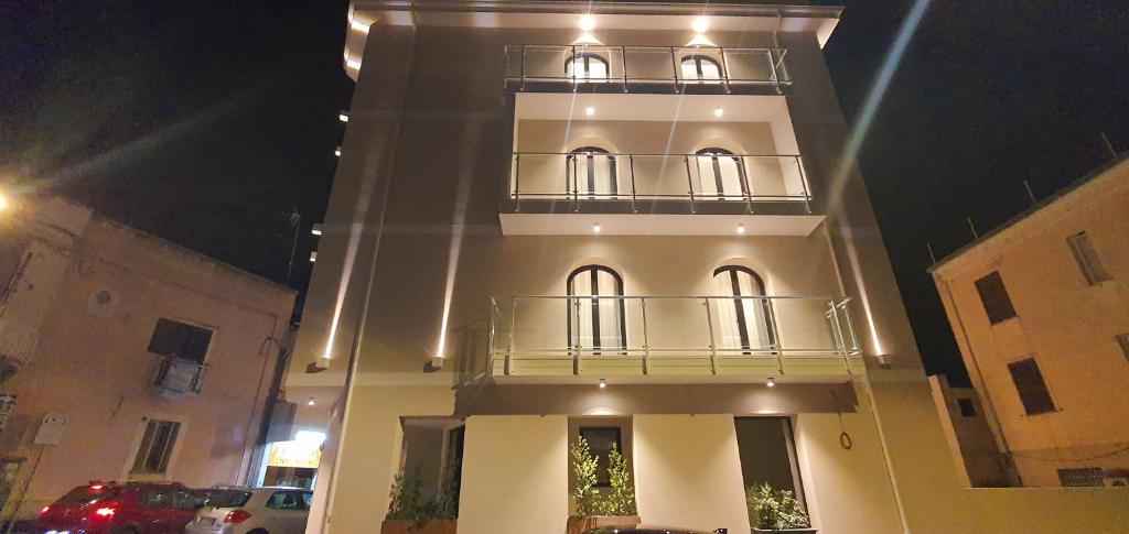 a tall white building with a balcony at night at Solmaris Tropea Rooms & Suites in Tropea