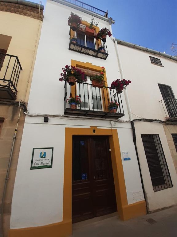 a building with a door and a balcony with flowers at Casa Manuel in Úbeda