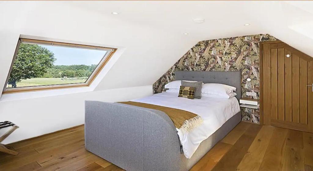 ein Schlafzimmer mit einem Bett in einem Zimmer mit einem Fenster in der Unterkunft The Pheasantry in Wymondham