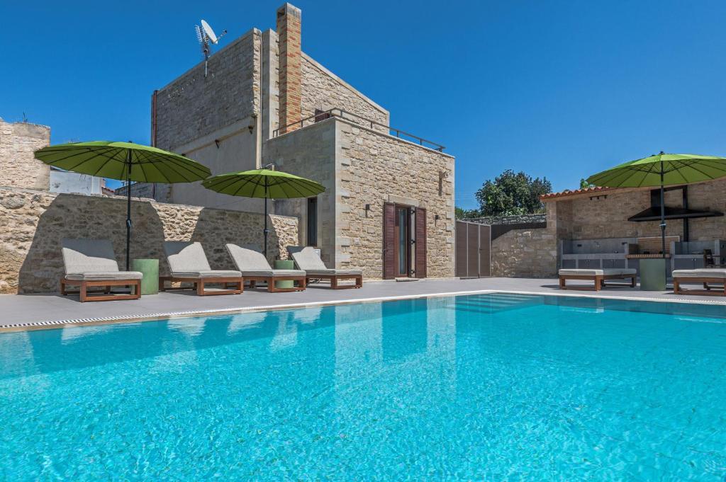 Villa Dim - With Private Pool في Margarítai: مسبح وكراسي ومظلات بجانب مبنى