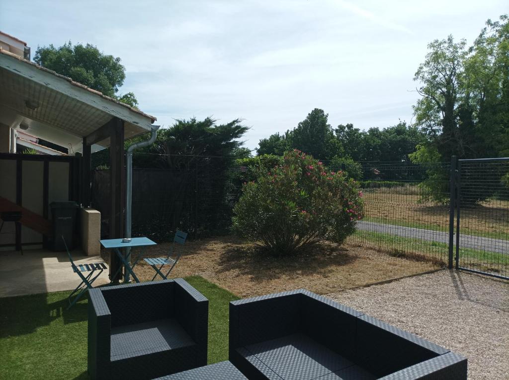 un jardín con 2 sillas, una mesa y una valla en Maison de vacance mi ville, mi campagne, en Boé