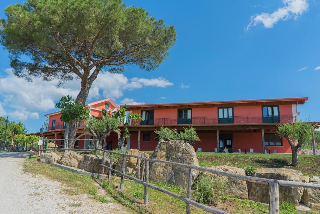 a red building with a tree in front of it at Terra di Vento in Montecorvino Pugliano