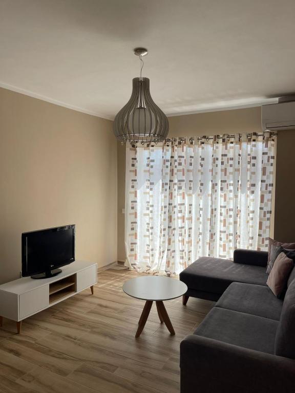 a living room with a couch and a tv and a table at Twentysix Apartment in Shkodër