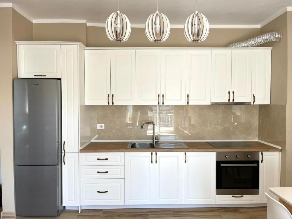 a kitchen with white cabinets and a stainless steel refrigerator at Twentysix Apartment in Shkodër