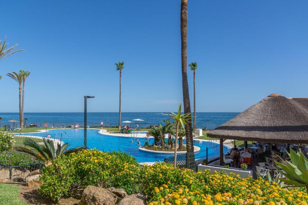 uma piscina de resort com o oceano ao fundo em Mi Capricho Playa Marbella em Sitio de Calahonda