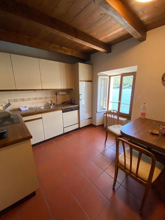 a kitchen with white cabinets and a red tile floor at Apartment in erster Seelinie in Morcote in Morcote