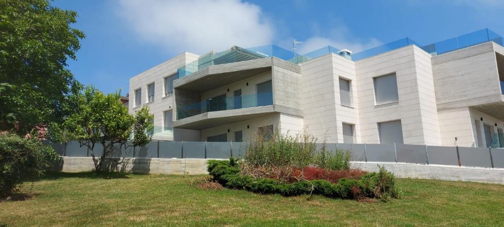 un gran edificio blanco con césped delante en Apartamentos modernos Residencial el Pinar en Liencres