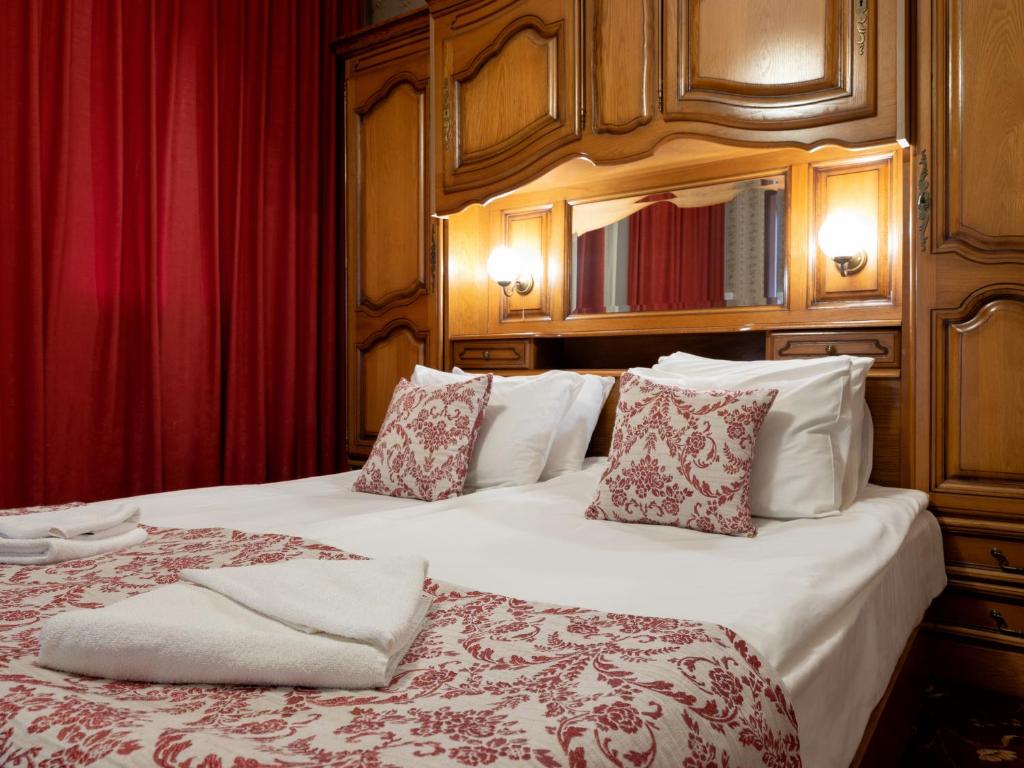 two beds in a hotel room with red curtains at Real Hotel in Veliko Tŭrnovo