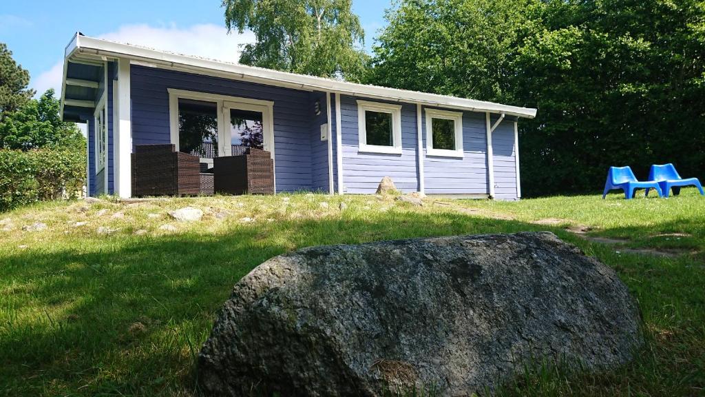 ein kleines blaues Haus mit einem großen Felsen davor in der Unterkunft dieSeeSucht - Lodge am Fjord in Westerholz