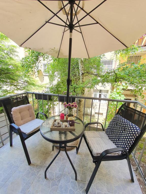 un patio con mesa, sillas y sombrilla en Apartments Aida, en Sarajevo