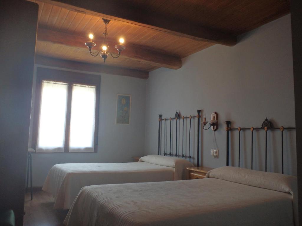 a bedroom with two beds and a chandelier at Guest House Joaco in Mansilla Mayor