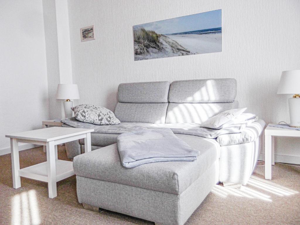 ein Wohnzimmer mit einem Sofa und einem Stuhl in der Unterkunft Haus Westwind Hallwegh 04 in Norderney