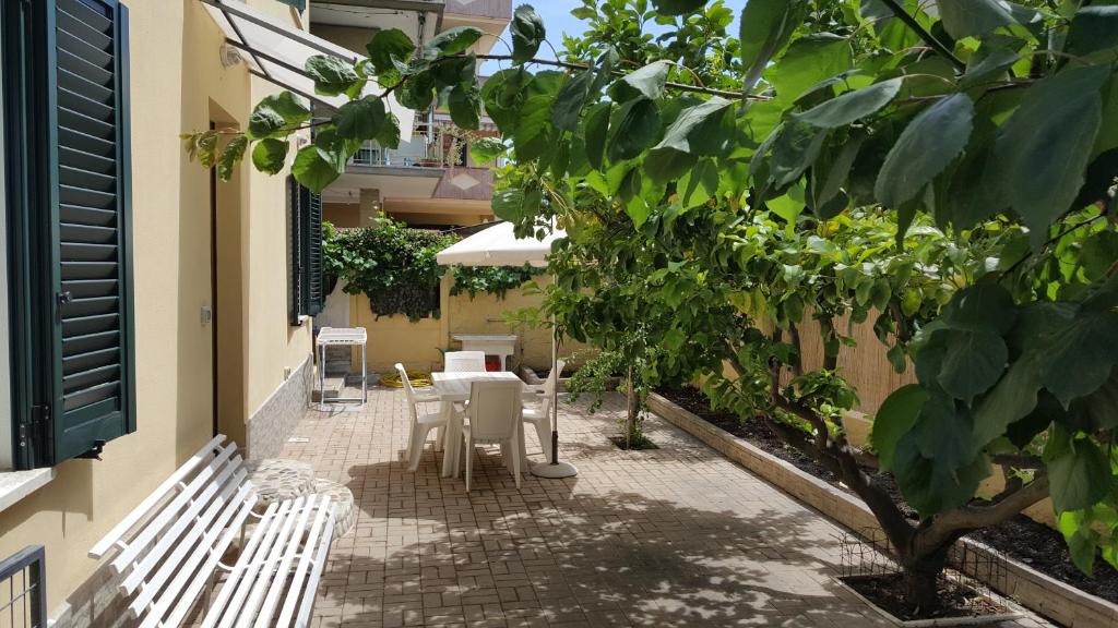 a patio with white chairs and a table and a tree at Appartamento Via Bixio in Roseto degli Abruzzi