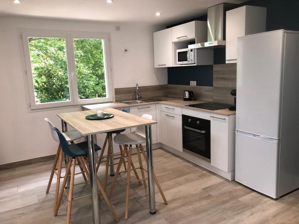 uma cozinha com uma mesa e cadeiras e um frigorífico em L'escapade em Saint-Léger-les-Mélèzes