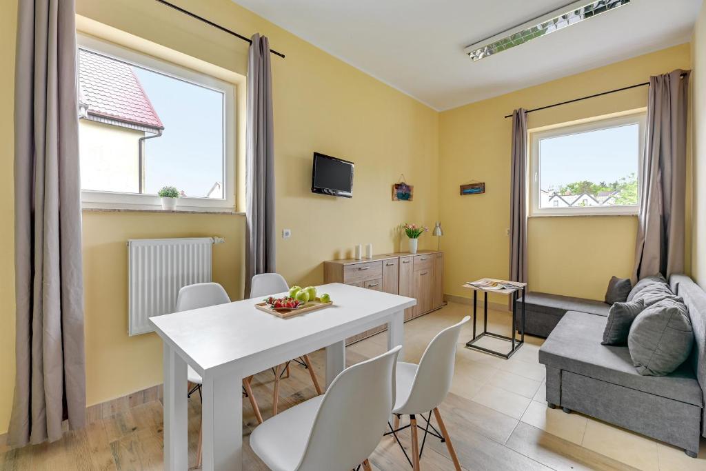 sala de estar con mesa blanca y sillas en Apartamenty Piamola Willa Zatoka, en Kąty Rybackie